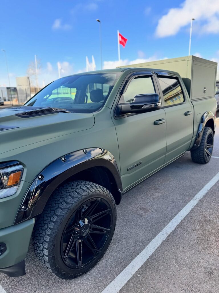 Närbild på mattgrön foliering bil med svarta skärmbreddare och detaljer på RAM pickup
