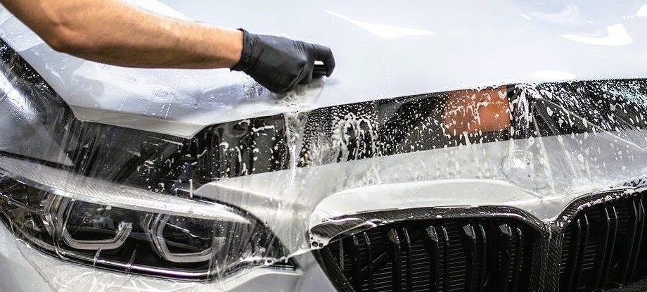 Vit BMW som får en PPF, paint protective film, applicerad på motorhuven